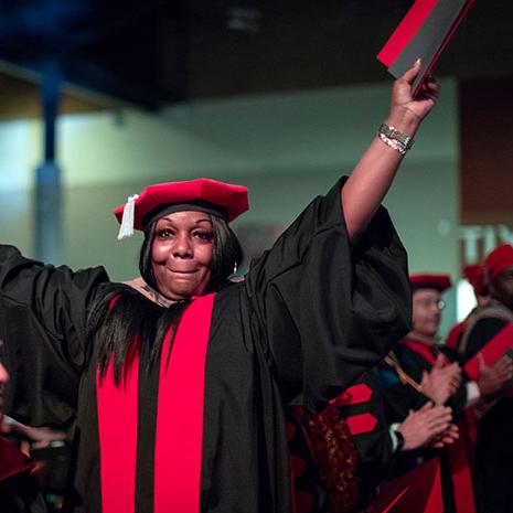 Graduating student holding their diploma and clapping